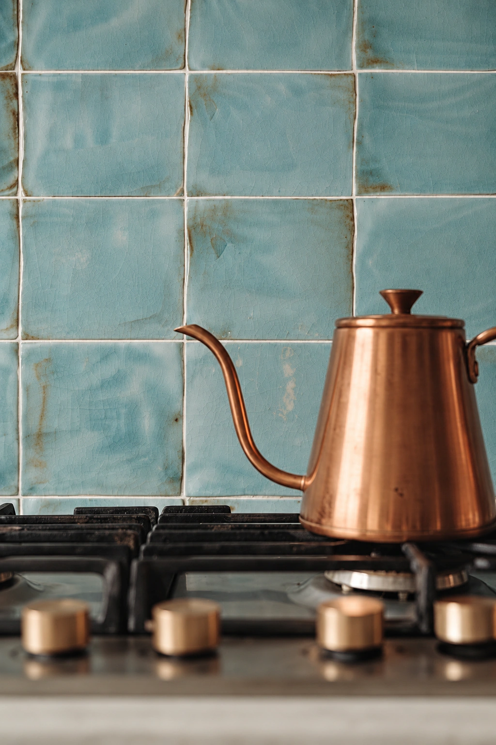 Cocina con azulejos turquesa y una tetera de cobre